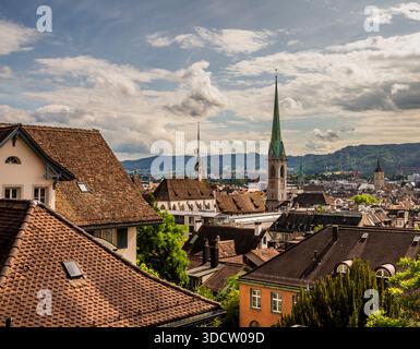 Blick auf Zürich, Schweiz, von der Polyterrasse an der Universität, Kirchtürme, Berge im Hintergrund, Dächer im Vordergrund und Wolken über blauem SK Stockfoto