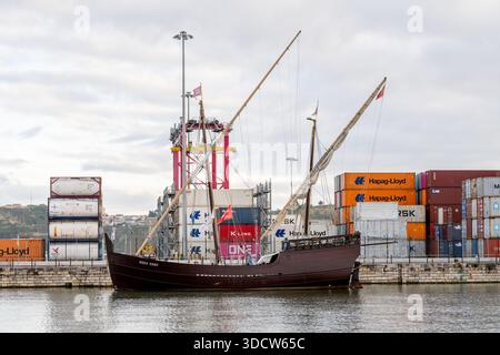 Lissabon Portugal 6. Dezember 2025. Ein traditionelles Segelschiff liegt auf dem Fluss mit gestapelten Schiffscontainern und Hafenkranen. Stockfoto