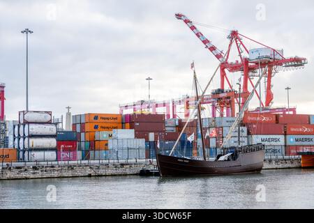 Lissabon Portugal 6. Dezember 2025. Ein traditionelles hölzernes Segelschiff liegt entlang der Uferpromenade mit gestapelten Containern und Frachtkranen i Stockfoto