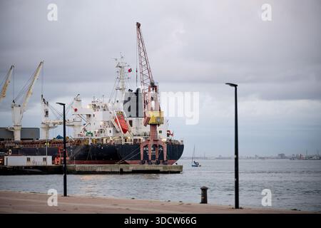 Lissabon Portugal 6. Dezember 2025. Ein großes Frachtschiff ist entlang des Tejo im Hafengebiet mit Kränen und Industrieinfrastrukturvisi angedockt Stockfoto