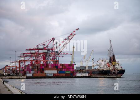 Lissabon Portugal 6. Dezember 2025. Containerkräne und gestapelte Schiffscontainer säumen die Hafenfront am Hafen entlang des Tejo. Stockfoto
