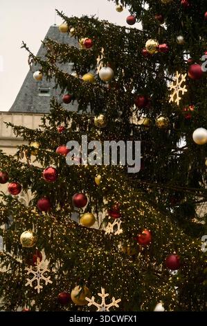 Nahaufnahme eines wunderschön dekorierten Weihnachtsbaums im Freien mit leuchtenden Lichtern, bunten Kugeln und beleuchteten Schneeflockenornamenten, ca. Stockfoto