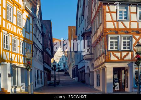 Enge Gasse gesäumt von orangen und gelben Fachwerkhäusern an einem sonnigen Tag. Stockfoto