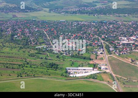 Dicht besiedeltes Dorf, umgeben von lebhaften grünen Feldern und sanften Hügeln. Häuser mit charakteristischen Ziegeldächern säumen verwinkelte Gassen Stockfoto