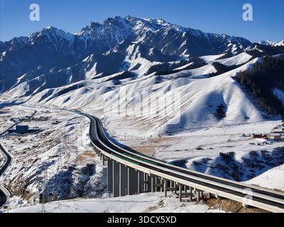 Peking, China. Dezember 2025. Eine Drohnenaufnahme vom 23. Dezember 2025 zeigt einen Blick auf den Urumqi-Yuli Expressway, der das Tianshan-Gebirge in der autonomen Region Xinjiang Uygur im Nordwesten Chinas durchquert. Der Tianshan Shengli Tunnel, der längste Schnellstraßentunnel der Welt, und der Urumqi-Yuli Expressway, der durch den Tunnel das Tianshan-Gebirge durchquert, werden bis Ende dieses Jahres für den Verkehr geöffnet sein, wodurch eine neue Verknüpfung zwischen den südlichen und nördlichen Teilen von Xinjiang ermöglicht wird. Quelle: Wang Fei/Xinhua/Alamy Live News Stockfoto