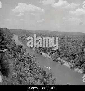 Ukraine, Region Donezk, Sviatohirsk, 1980er Jahre Ein archiviertes Schwarzweißfoto, das einen majestätischen Panoramablick auf den Seversky Donets River von den Kreidefelsen aus macht. Ein kleines Vergnügungsboot fährt entlang des gewundenen Wassers, umgeben von den üppigen dichten Wäldern des Naturschutzgebietes der Heiligen Berge. Diese alte Luftlandschaft vermittelt die ruhige Schönheit des beliebten Resorts. Es dient als wertvolles historisches Dokument der Natur und des Tourismus im friedlichen Donbass vor dem Krieg. Stockfoto