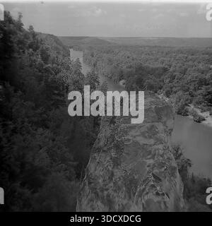 Ukraine, Region Donezk, Sviatohirsk, 1980er Jahre Ein archiviertes Schwarzweißfoto, das einen dramatischen Blick auf den Seversky Donets River von den Kreidefelsen aus zeigt. Eine massive, zerklüftete Felsformation dominiert den Vordergrund und hebt die einzigartigen geologischen Merkmale des Naturschutzgebiets der Heiligen Berge hervor. Dahinter fließt der sich windende Fluss durch dichte, üppige Wälder unter einem bewölkten Himmel. Diese alte Landschaft bewahrt die wilde Schönheit der Natur in einem friedlichen Donbass vor dem Krieg und diente als historisches Dokument. Stockfoto