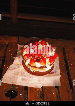 Hausgemachter Erdbeerkuchen mit Schlagsahne auf Holztisch Stockfoto