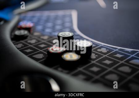 Casino Poker Tisch Nahaufnahme mit Stapel von Glücksspielchips auf Filzoberfläche mit Farbmarkierungen und unscharfem Hintergrund, professionelles Kartenspiel setti Stockfoto