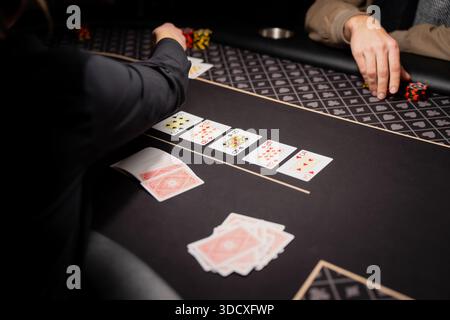 Casino-Poker-Tischszene mit Händlern und Spielern mit offengelegten Spielkarten und gestapelten Chips, professioneller Spielumgebung erfasst von Stockfoto