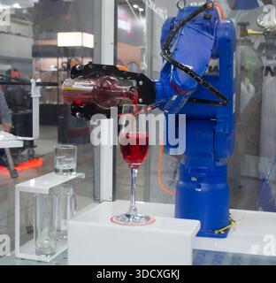 Robotermanipulatoren. Roboter, der flüssiges Getränk aus der Flasche in das Glas gießt. Industrieroboter. Roboterarm Hand. Industrielle Manipulatoren für das vielfältige Schweißen Stockfoto