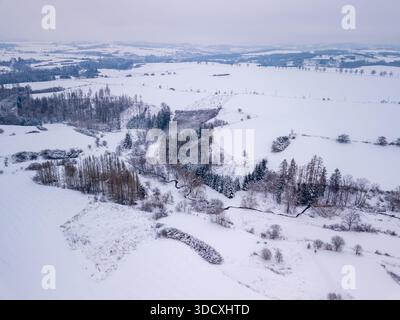 Aus der Vogelperspektive auf eine schneebedeckte Winterlandschaft mit einem Fluss, der sich durch Hügel und Wälder in Tschechien schlängelt. Hochland, Vysocina, Tschechische Republik Stockfoto