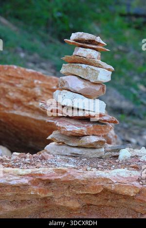 Natürliche flache Gesteinsformation, die übereinander gestapelt ist und einen Steinhaufen bildet. Die Felsen zeigen abwechselnd rötlich-braune und blassweiße Farbtöne. Stockfoto
