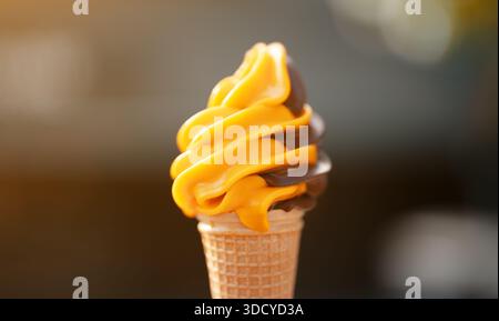 Geschwenkte Schokolade und Orangeneis in Waffelkegel servieren. Stockfoto