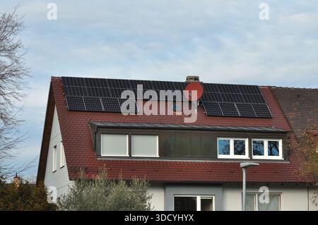 Privates Wohnhaus mit Solarpaneelen auf einem schrägen Dach. Das Bild stellt die Nutzung erneuerbarer Energien im städtischen Wohnraum dar, Showin Stockfoto