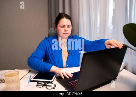 Remote-Mitarbeiter, der die Arbeit von zu Hause aus beginnt. Zielgerichtete Frau, die im Home Office den Computer anschaltet. Moderne Arbeit von zu Hause aus Stockfoto