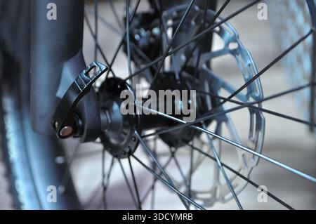 Nahaufnahme eines Vorderrads eines Fahrrads mit Scheibenbremse, Speichen und Achsnabe. Detailansicht moderner Fahrradmechanik und technischer Konstruktion. Stockfoto