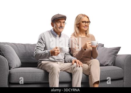 Ein älteres Paar sitzt auf einem Sofa und trinkt Kaffee oder Tee isoliert auf weißem Hintergrund Stockfoto