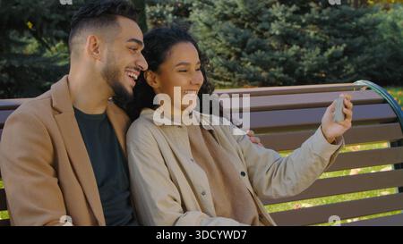 Fröhliches hispanisches Paar sprechen Videoanruf mit Handy-App virtueller Webchat lächelnd Aufnahme Social Media Vlog in Stadt Herbst Park Mann und Frau Stockfoto