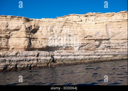 Spektakuläre Kreidefelsen und zerklüftete Kalksteinfelsen der Halbinsel Delimara an der südöstlichen Spitze Maltas, fotografiert vom Meer aus in der Sonne Stockfoto