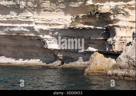 Spektakuläre Kreidefelsen und zerklüftete Kalksteinfelsen der Halbinsel Delimara an der südöstlichen Spitze Maltas, fotografiert vom Meer aus in der Sonne Stockfoto