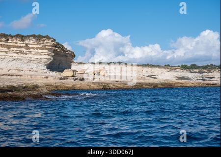 Spektakuläre Kreidefelsen und zerklüftete Kalksteinfelsen der Halbinsel Delimara an der südöstlichen Spitze Maltas, fotografiert vom Meer aus in der Sonne Stockfoto