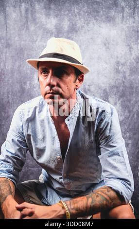 Der Mann trug ein weißes und hellblaues Sommerhemd und einen weißen Fedora. Der Mann ist vierzig Jahre alt und kaukasischer Herkunft Stockfoto