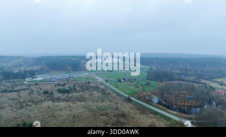 Aus der Vogelperspektive eines belarussischen Herrenhauses zeigt einen weißen neogotischen Palast auf Terrassen, ausgerichtet an einer geraden Allee, Nadelwald, Felder, Straßen, Parkplätze, Stockfoto