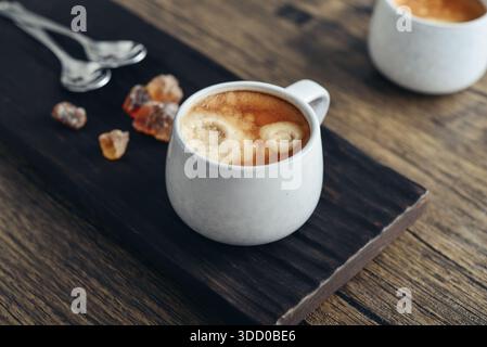 Zwei Tassen Kaffee auf Holztablett mit Steinrohrzucker Stockfoto