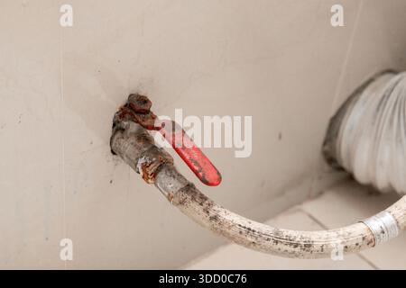 Toilettenwasserzuleitung. Wasserventil am Toiletteneinlass mit Geflechtschlauch. Vertikale Montage des Kugelhahns mit Wasserleitung vom Boden. Toilette Stockfoto