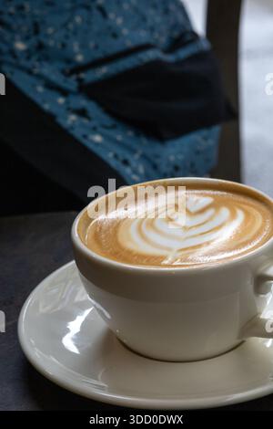 Nahaufnahme eines heißen Cappuccinos mit wunderschöner Latte Art in einer weißen Keramikschale Stockfoto