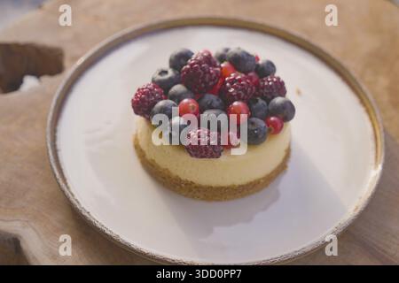 Käsekuchen mit frischen Beeren auf einem Holztisch Stockfoto