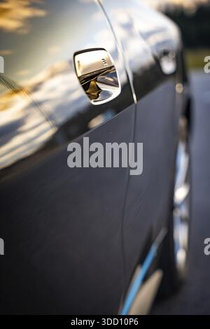 Nahaufnahme einer Autotür mit Sonnenuntergang-Reflexen auf der Farbe, BMW i7 Elektroauto, Deer e-Carsharing, Calw, Deutschland Stockfoto