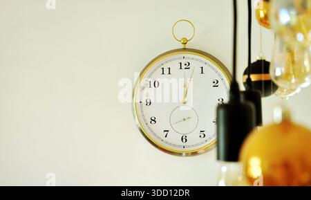Die Uhr schlägt zwölf, drei Minuten nach Mitternacht. Rund um die Uhr an einer hellen Wand, Mitternacht, Silvesterkonzept. Fragment der häuslichen Umgebung Stockfoto