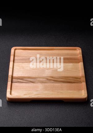 Ein leeres quadratisches Holztablett oder -Teller, Küchenutensilien für die Zubereitung von Lebensmitteln. Ein leeres Holztablett als Lebensmittelhintergrund für Ihr Design Stockfoto