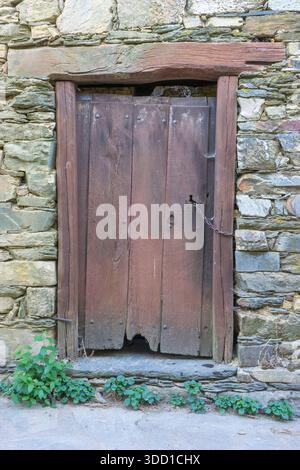 Eine rustikale Holztür in einer Steinmauer, braun Stockfoto
