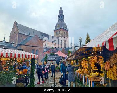 Gäste der baltischen Hauptstadt besuchen den Weihnachtsmarkt auf dem Kuppelplatz von Riga, Lettland Stockfoto