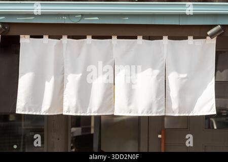 Der Vorhang-ähnliche Stoff, der vor traditionellen japanischen Restaurants und Geschäften hängt, dient nicht nur als Schild, sondern hat eine größere Bedeutung, Stockfoto