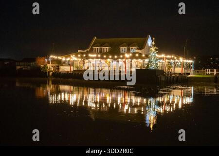 Rise Restaurant in West Bay, ein rustikales Restaurant am Fluss mit Terrasse, das globale Gerichte zum Frühstück, Mittag- und Abendessen serviert, beleuchtet am Abend. Stockfoto