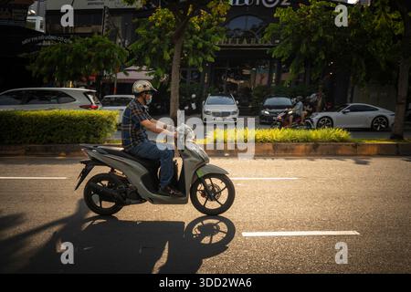 Der Mann fährt auf einer Straße mit dem Motorrad. Der Mann trägt einen Helm und ein kariertes Hemd. Das Motorrad steht am Straßenrand Stockfoto