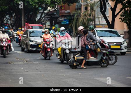 Geschäftige Straße mit vielen Motorrädern und Autos. Die Leute auf den Motorrädern tragen Masken. Die Szene ist voll und chaotisch Stockfoto
