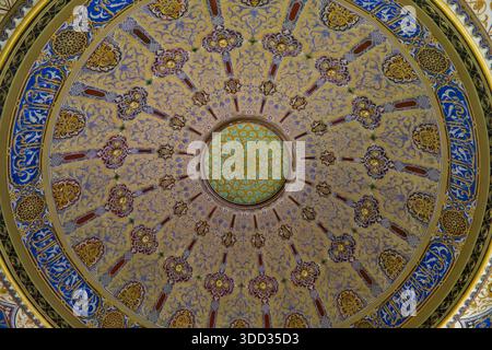 Ein atemberaubender, flacher Blick auf eine kunstvolle Kuppel im osmanischen Stil mit kreisförmigem Muster, mit komplexen Gold- und blauen Mosaikfliesen. Stockfoto