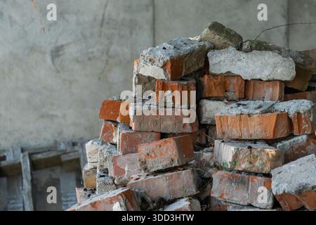 Anhäufung alter Ziegelsteine und Betonschutt im unfertigen Gebäude, Bauabfälle und Renovierungshintergrund Stockfoto