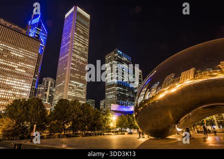 Cloud-Gate-Skulptur im Millennium Park, die beleuchtete Hochhäuser der Innenstadt und die Platzbeleuchtung in der Nacht reflektiert. Stockfoto