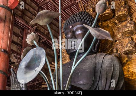 Das Gesicht des Großen Buddhas (Rushana Butsu) erhebt sich vor einer vergoldeten Mandorla, die mit kleinen Buddha-Figuren verziert ist, im Daibutsuden des Tempels Todai-ji in Nara, Japan. Die 1752 gegossene Bronzestatue von etwa 15 Metern Höhe gilt als die größte ihrer Art weltweit. Stockfoto