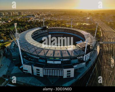 Eine Drohnenaufnahme fängt das Melbourne Cricket Ground Stadion, die umliegende Stadt und die Bahngleise während eines hellen Sonnenaufgangs der goldenen Stunde ein. Stockfoto