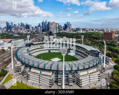 Ein Blick aus der Vogelperspektive zeigt den weitläufigen Melbourne Cricket Ground, umgeben von einer Parkanlage, mit dem unverwechselbaren Stadtbild in der Innenstadt unter hellem Himmel. Stockfoto