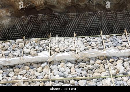 Nahansicht mit Konstruktion starke Stützwand aus Steingestein und Gitterverstärkung aus Metalldraht auf Boden Boden im Freien Sit Stockfoto