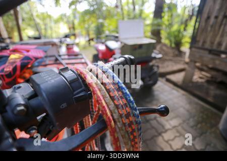 Nahaufnahme zeigt ein buntes Bungee-Seil, das um den Lenker des Fahrzeugs gewickelt ist, mit abenteuerlichem Feeling und unscharfem Hintergrund der Natur im Wald Stockfoto