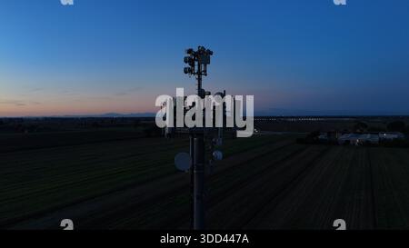 Mobilfunkturm steht vor dem dunkelblauen Himmel, ausgestattet mit verschiedenen Antennen für drahtlose Kommunikation und Mobilfunkdienste im gesamten Po Val Stockfoto